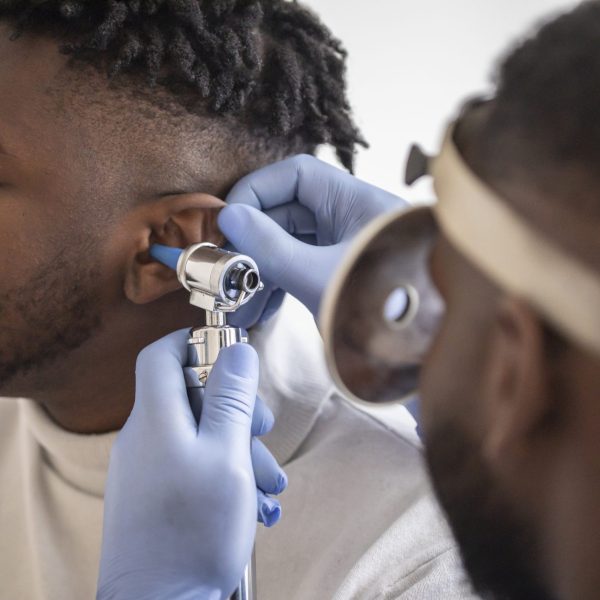 Close up of a doctor checking the ear of his male patient Close up of a male doctor carefully holding the ear of his patient to establish a clearer view of the inside of his ear, to see if he requires hearing aids at a modern clinic